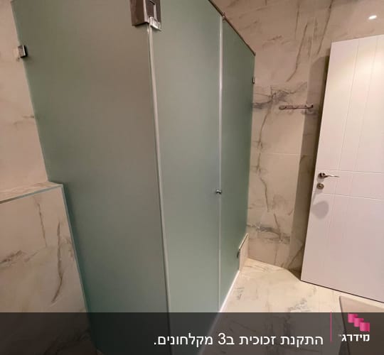 מקלחון זכוכית בחדר אמבטיה מודרני עם קירות שיש.